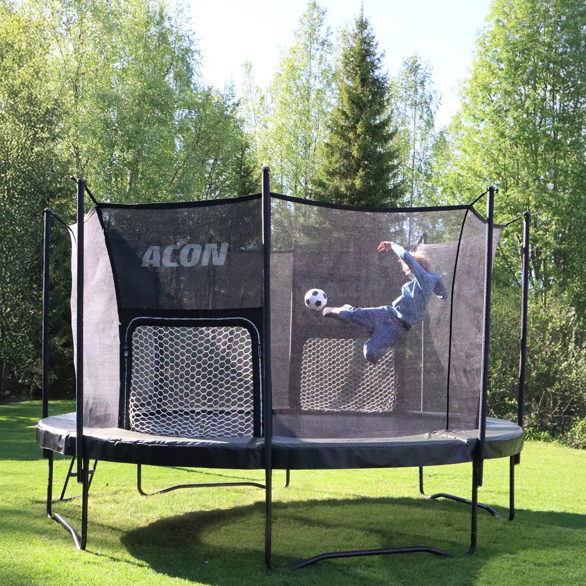 Enfant donnant un coup de pied dans un ballon en direction de but de football ACON Air pour trampolines ronds ACON Air à l’intérieur d’un trampoline.