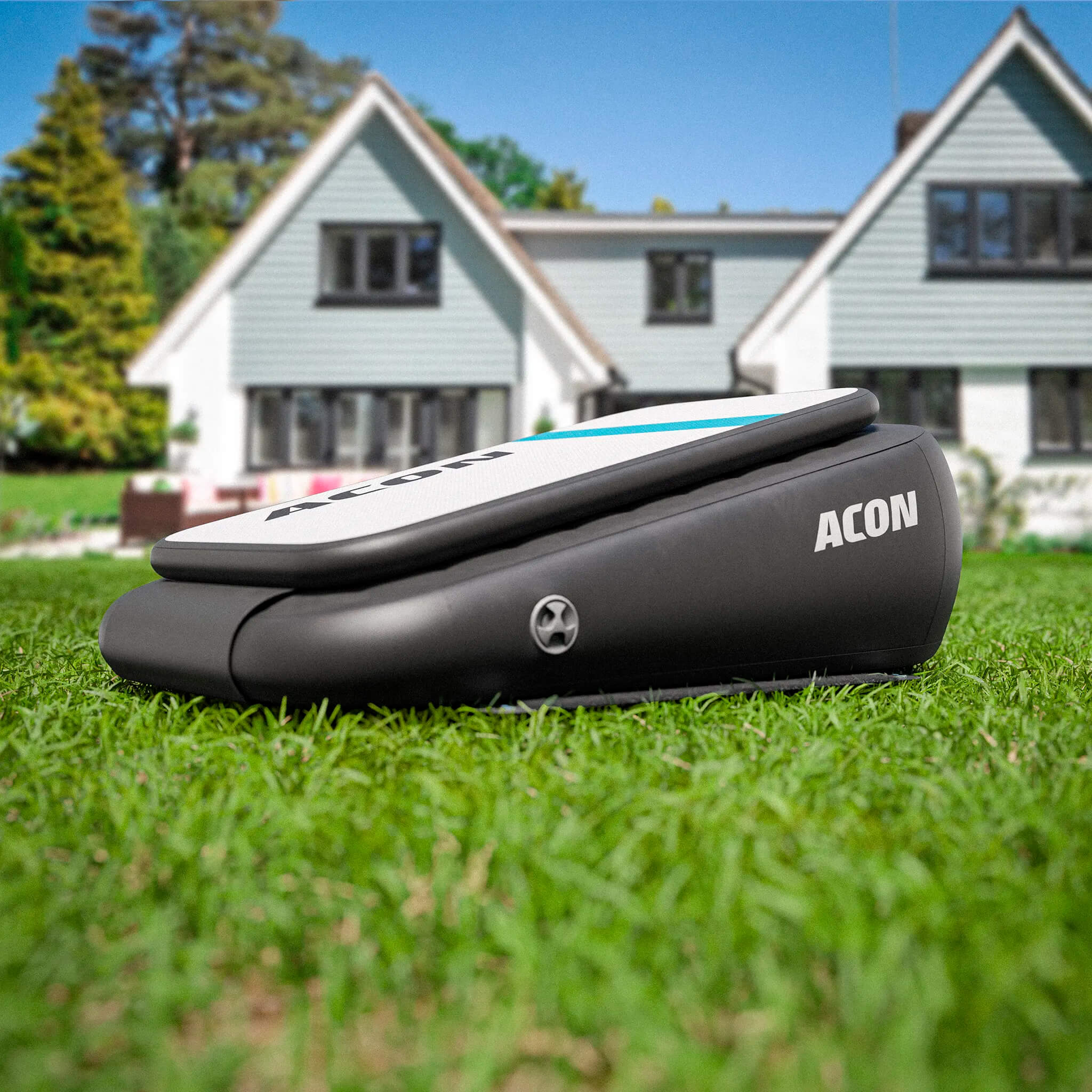 ACON Airboard sur l’herbe dans un jardin ensoleillé, avec une grande maison en arrière-plan. 
