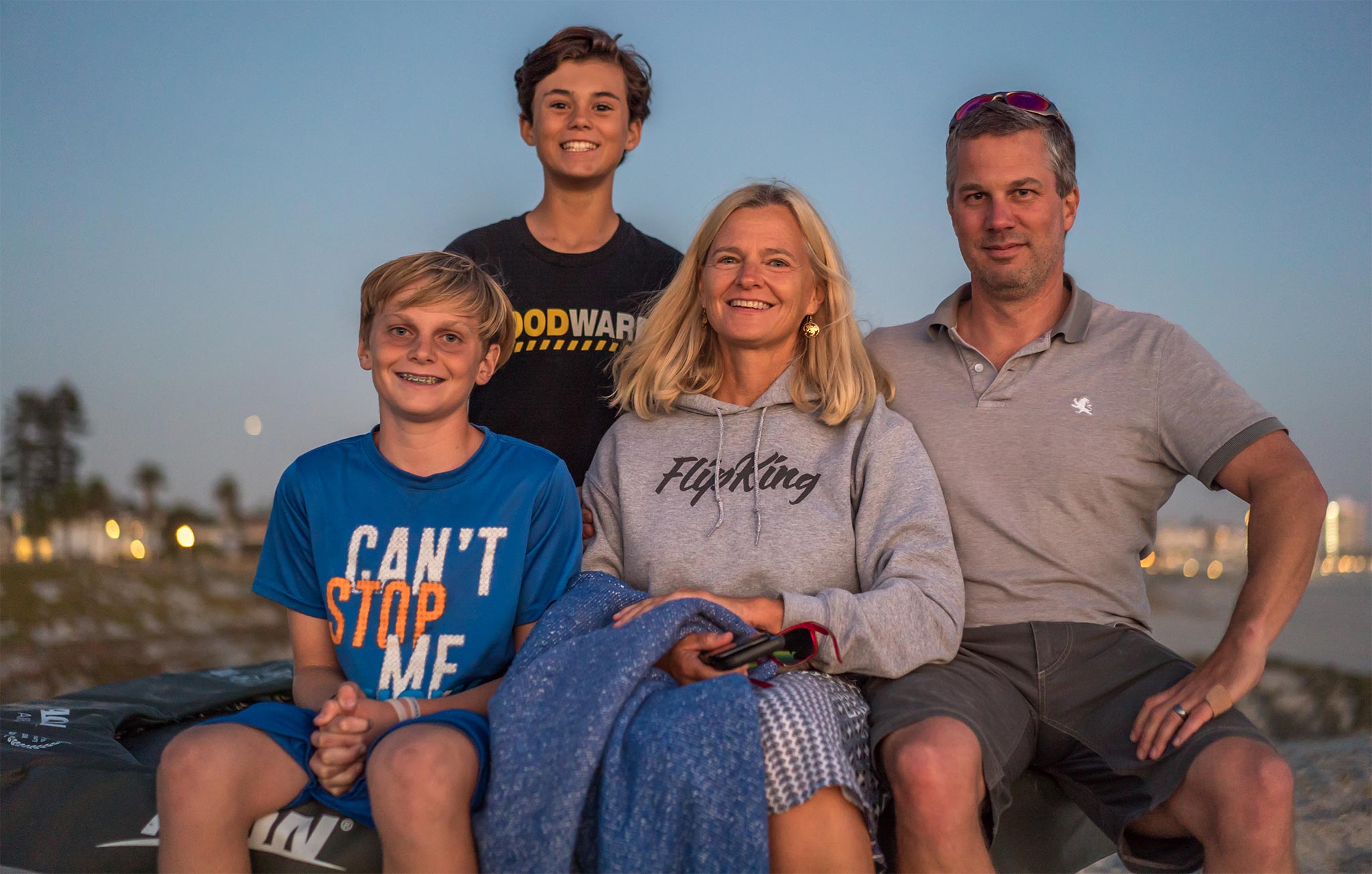 Une famille de clients Acon, composée d’une mère et de ses trois garçons, tous assis sur une plage