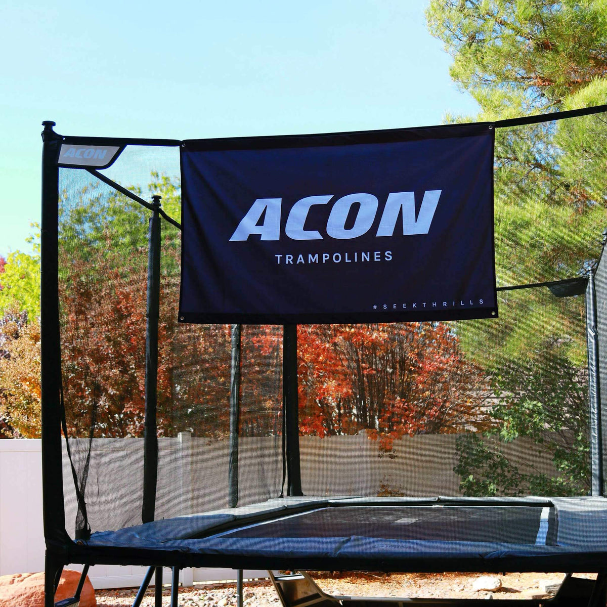 Drapeau ACON noir fixé au filet de sécurité du trampoline.