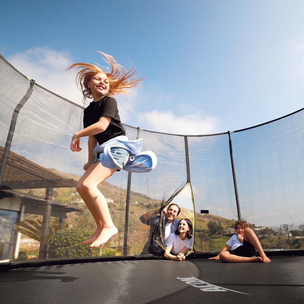 Une fille sautant sur un trampoline Acon pendant que sa famille la regarde 