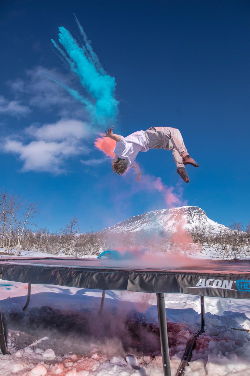 Une personne en plein rebond sur un trampoline ACON à Lapland, en Finlande, avec des traînées de couleur bleues et rouges en arrière-plan 