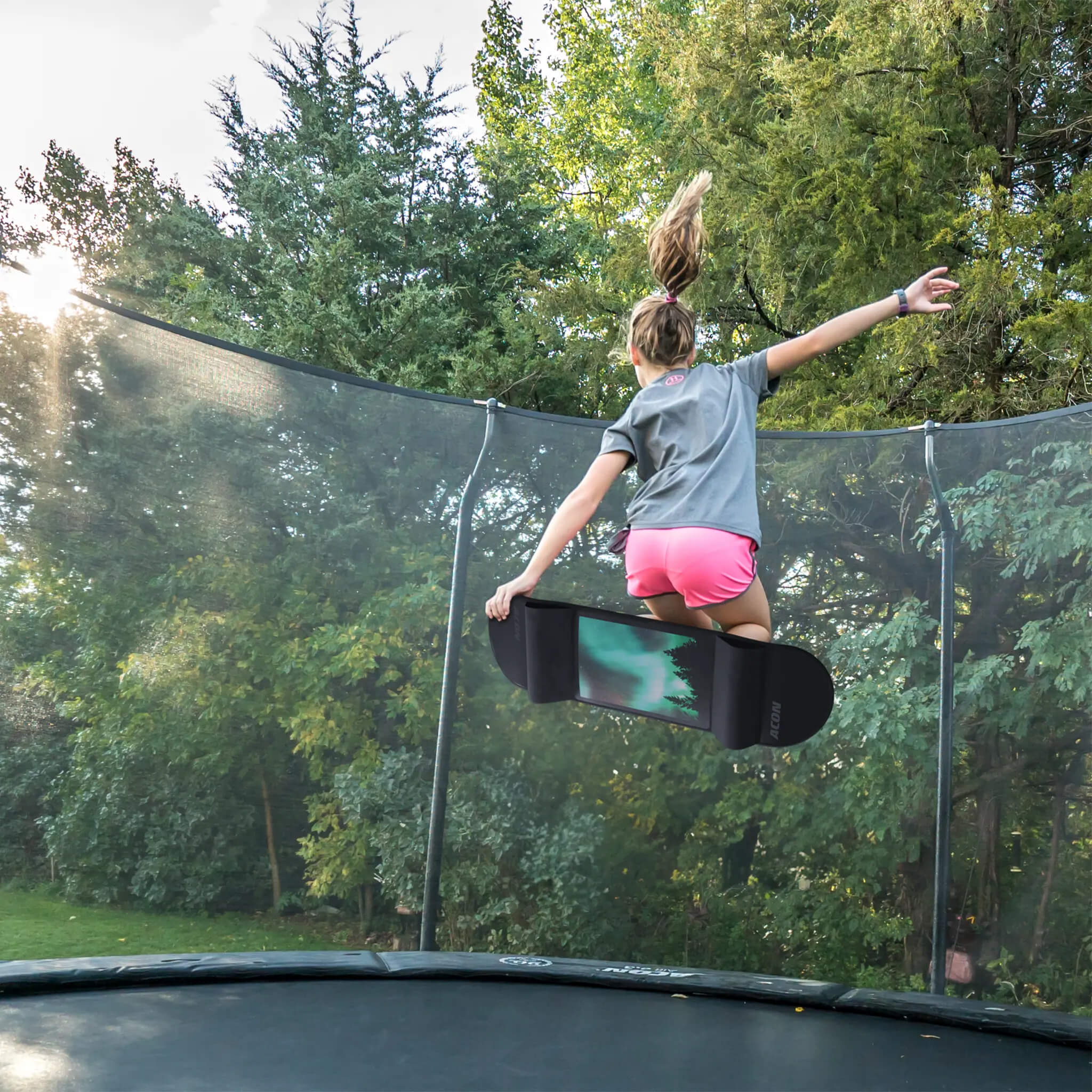Une fille saute sur un trampoline avec un Skateboard Pour Trampoline Acon.