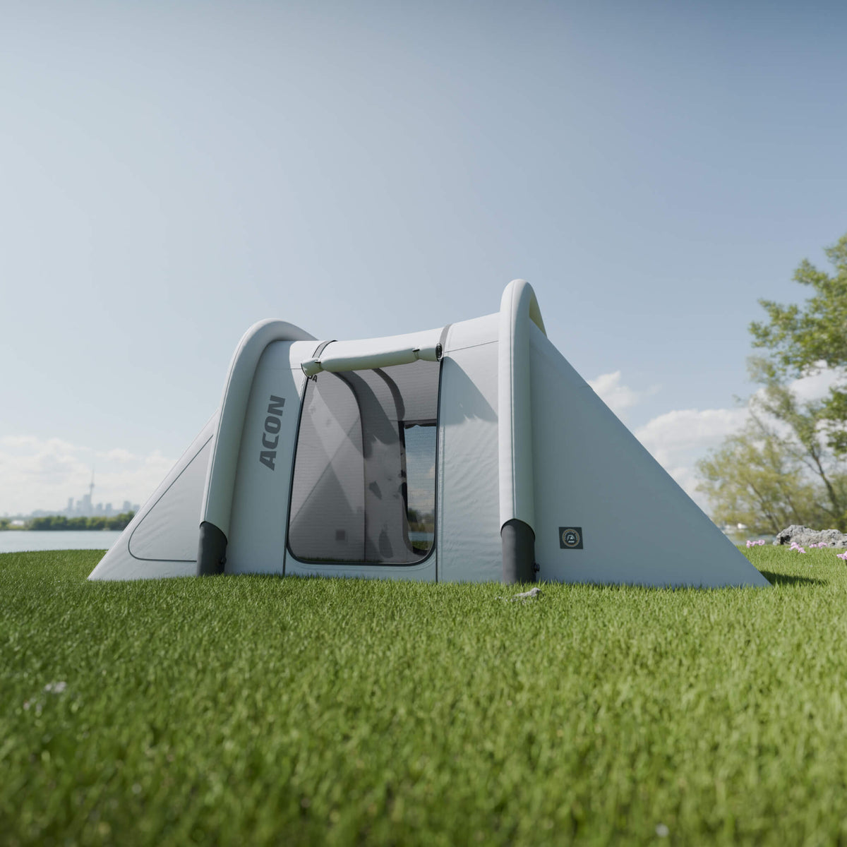 Tente de trampoline rectangulaire Acon installée sur une pelouse verdoyante, de couleur grise et blanche avec des fenêtres en filet transparent. Le design épuré et moderne de la tente, placée sous un ciel bleu, met en valeur sa compatibilité avec l’extérieur et son intérieur spacieux. 