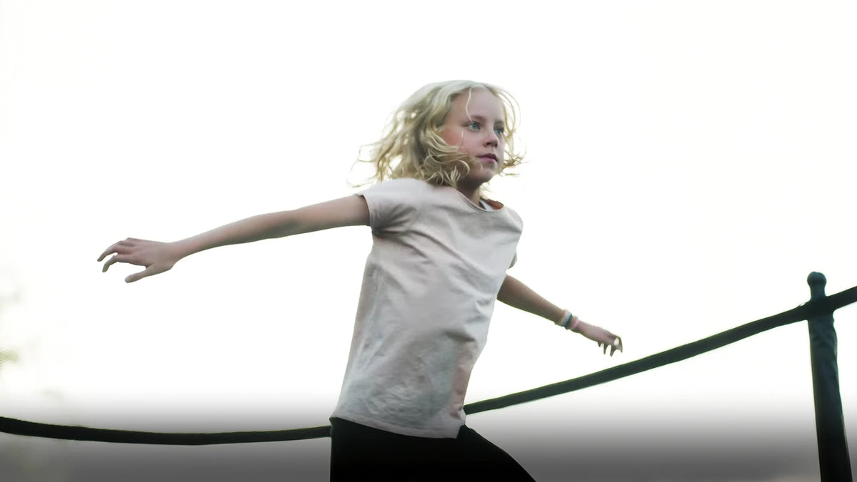 Fille sautant sur un trampoline Acon avec un regard concentré.