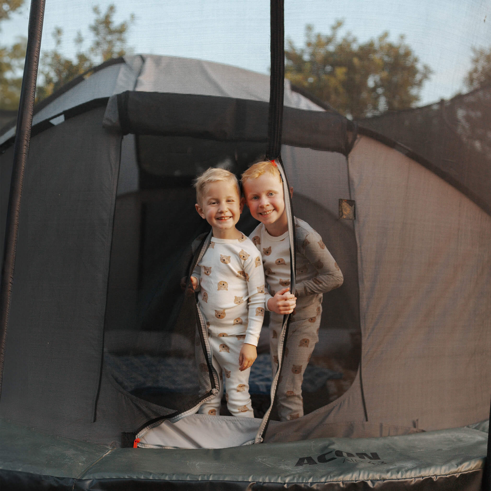 Deux enfants se tiennent dans l'entrée de la tente de trampoline Acon.