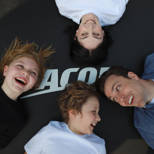 Visages heureux d’une famille allongée sur le trampoline Acon
