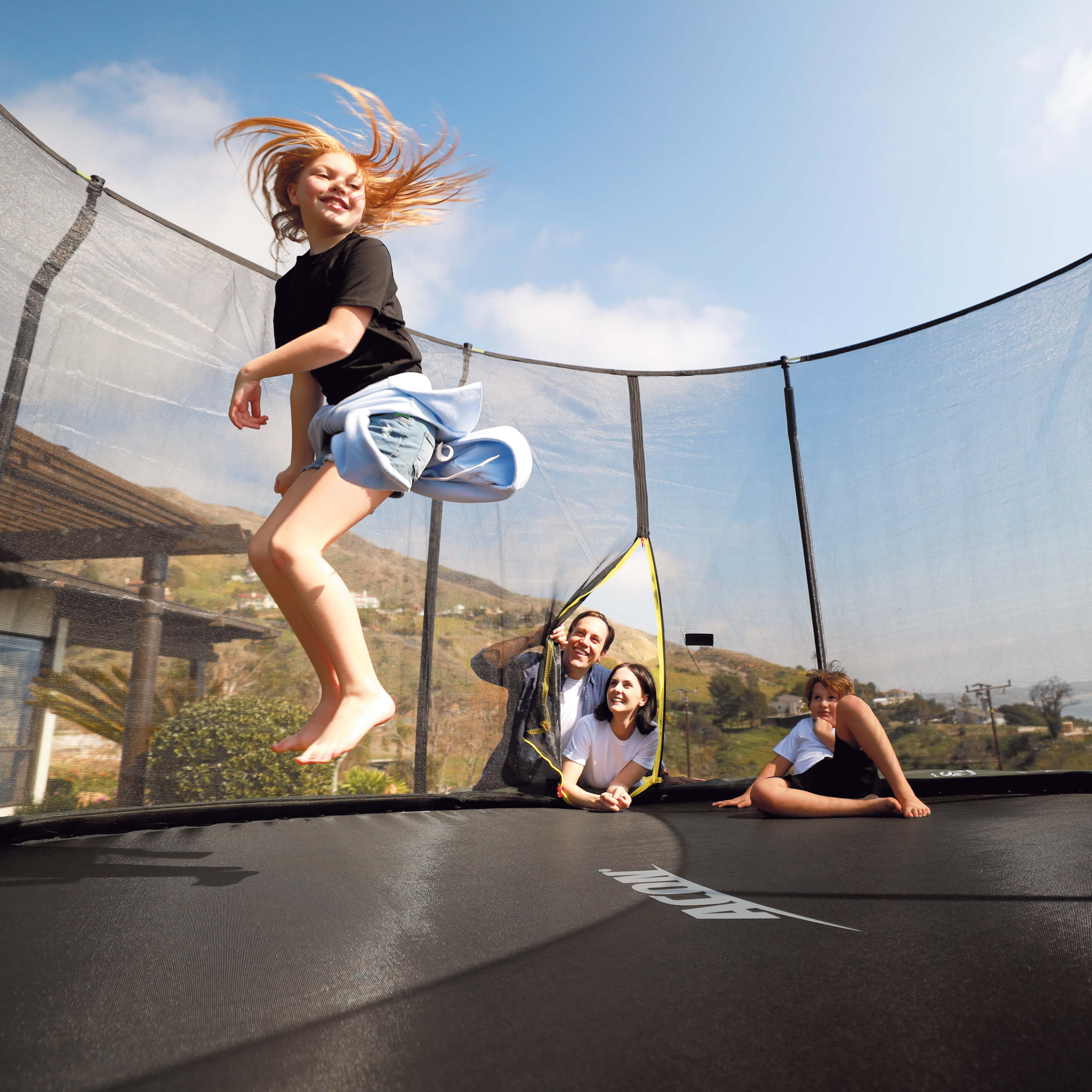 Une fille saute sur un trampoline Acon, la famille regarde.