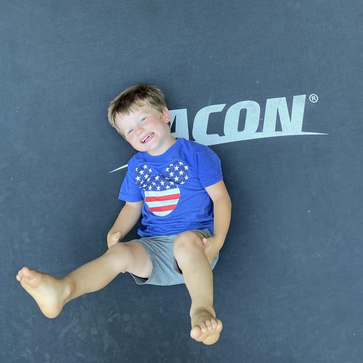 Un garçon heureux allongé sur un trampoline Acon.