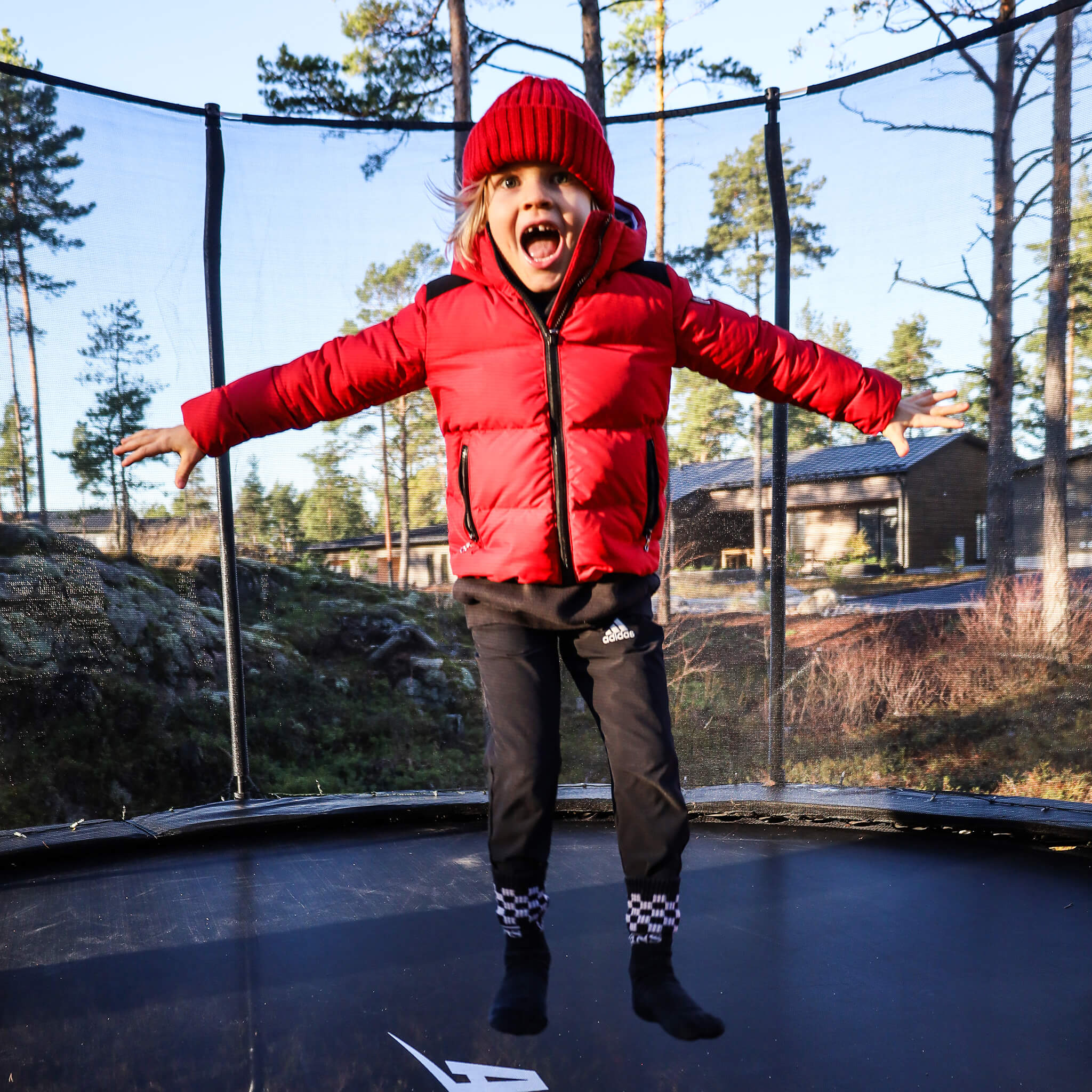 Une fille en veste rouge saute sur un trampoline Acon.