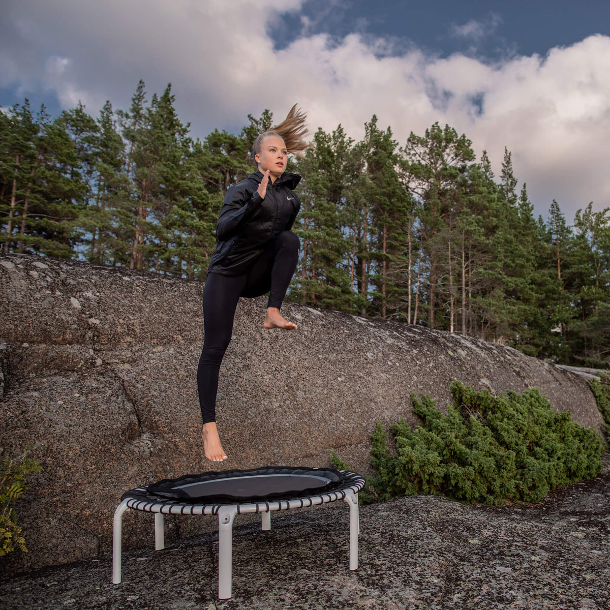 Une femme fait de la gymnastique sur un rebounder Acon FIT dans le salon.