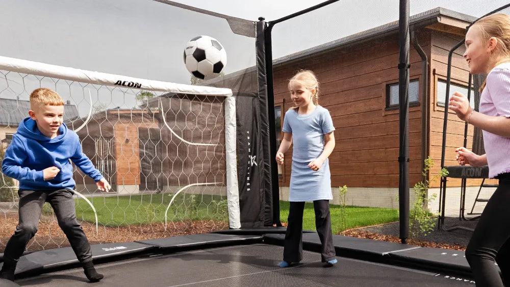 Des enfants jouent au football sur un trampoline Acon X équipé de l’ACON Soccer Goal.