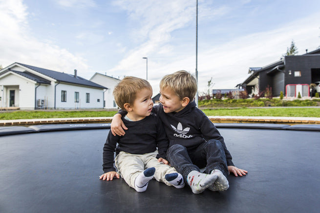 Deux enfants assis et enlacés sur un trampoline rond