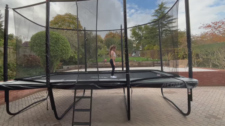 Une petite fille effectue des saltos et des roues sur un trampoline Acon 16HD à l’extérieur, sous une lumière vive.
