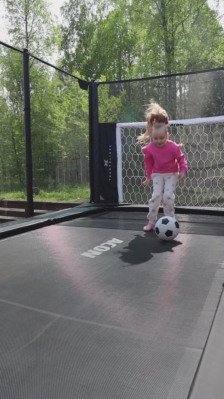 Une petite fille saute sur un trampoline Acon X et joue au football sur trampoline.