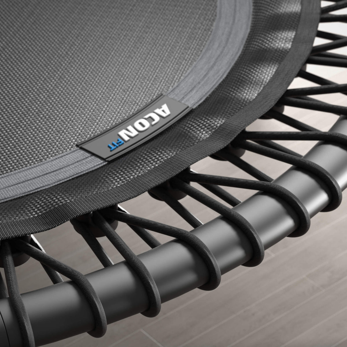 Gros plan sur les cordes élastiques d’un trampoline Acon FIT noir et rond.