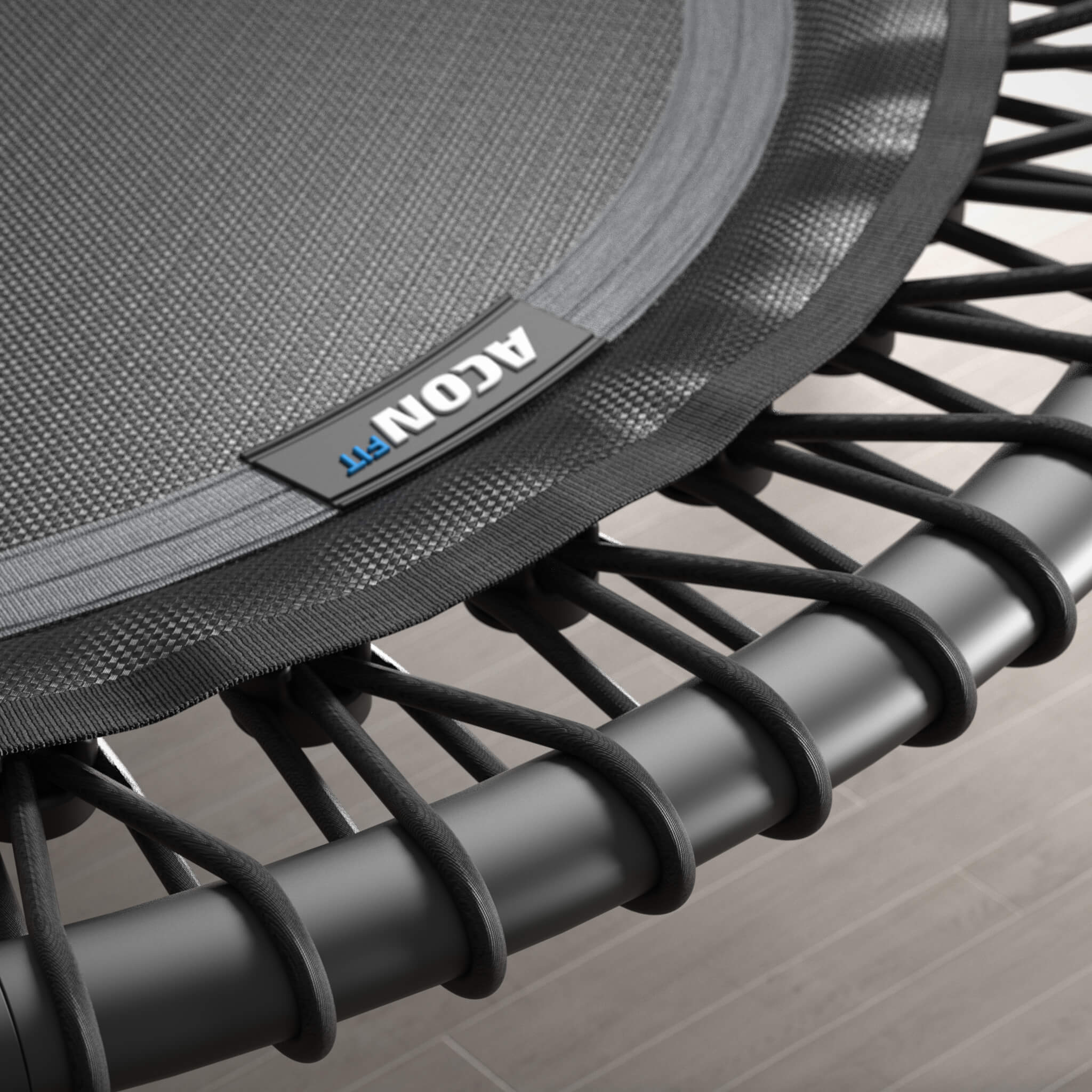 Gros plan sur les cordes élastiques d’un trampoline Acon FIT noir et rond.