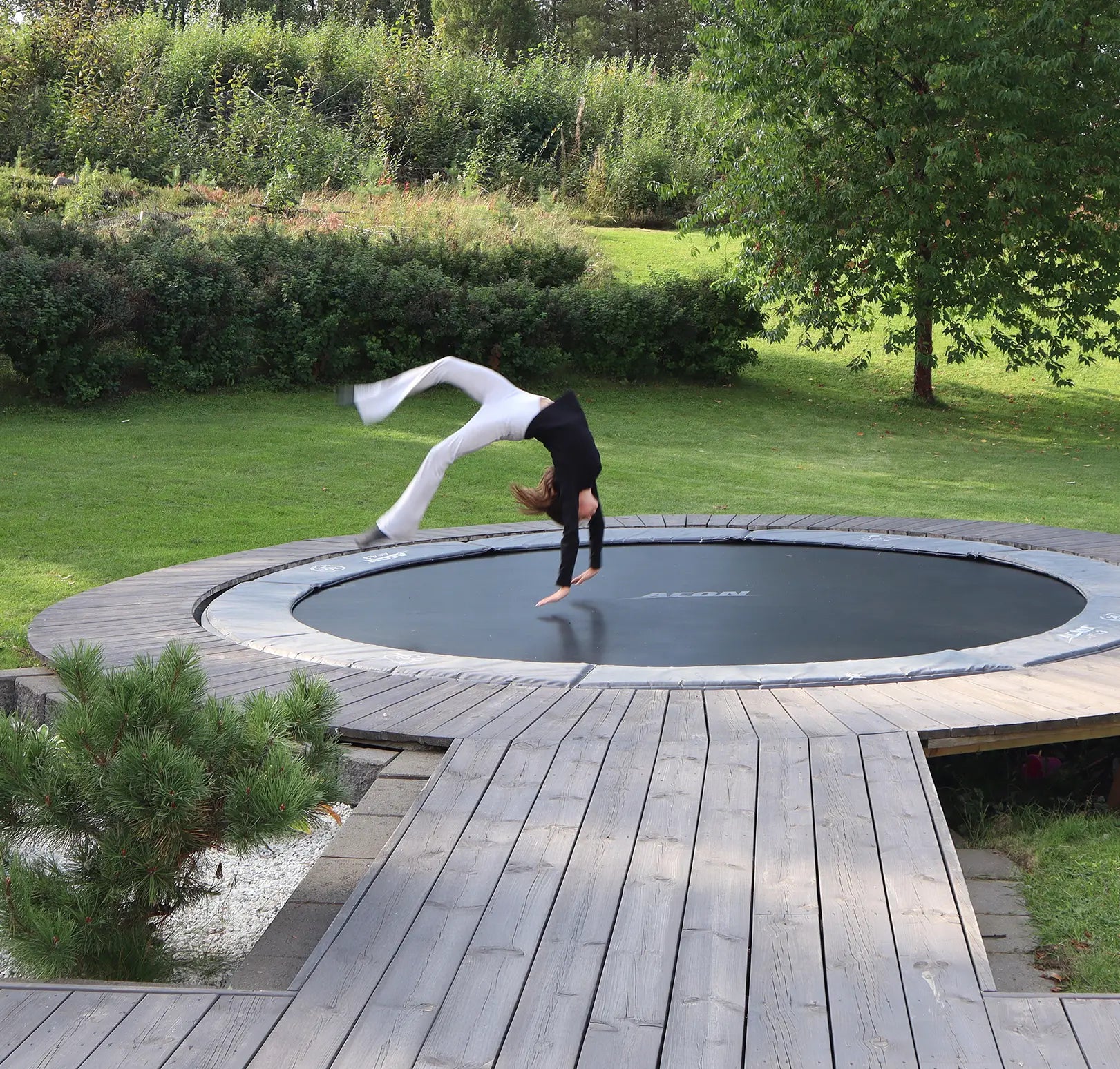 Une fille sautant sur un trampoline encastré dans la terrasse de l'arrière-cour.