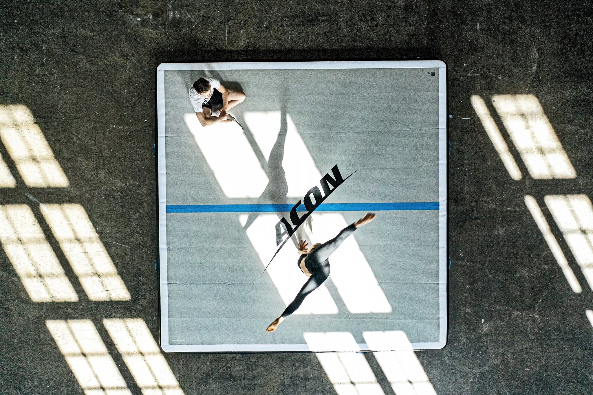 Une gymnaste en pleine figure sur un grand tapis Acon airtrack. 