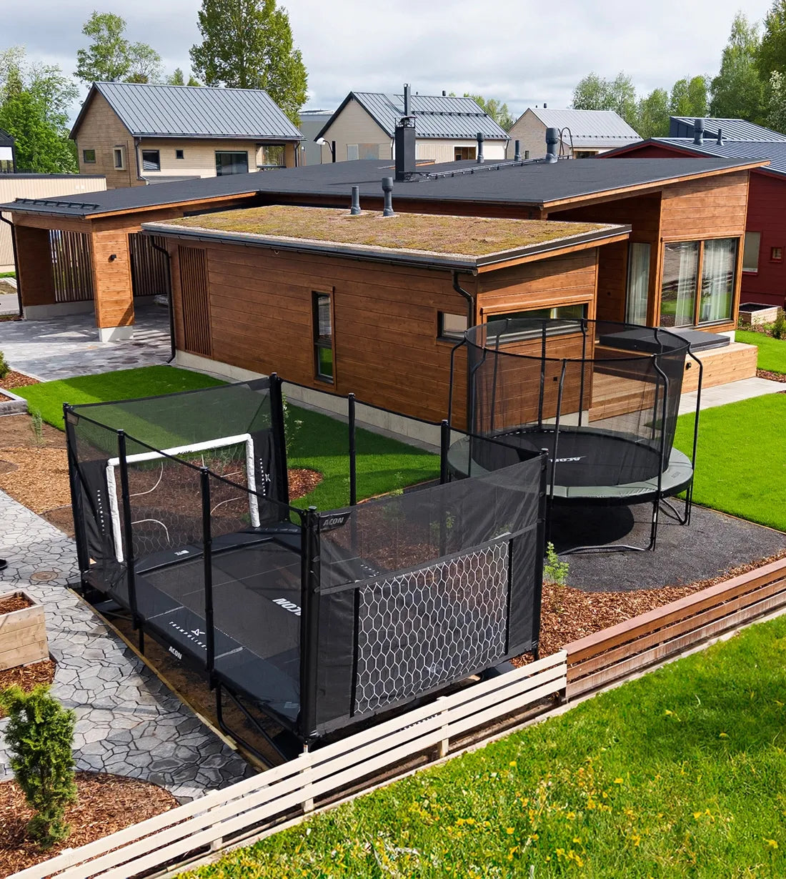 Deux trampolines Acon dans le jardin d'une maison moderne. L'un d'eux est partiellement encastré.