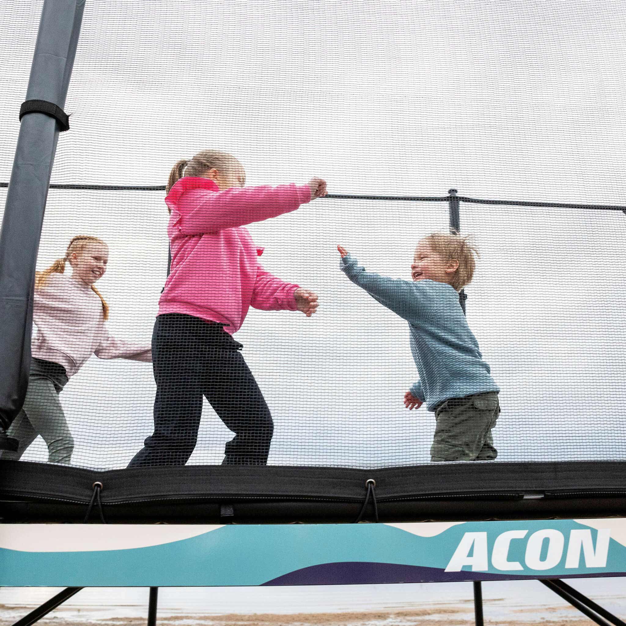 Trois enfants jouent sur l'Acon X Trampoline.