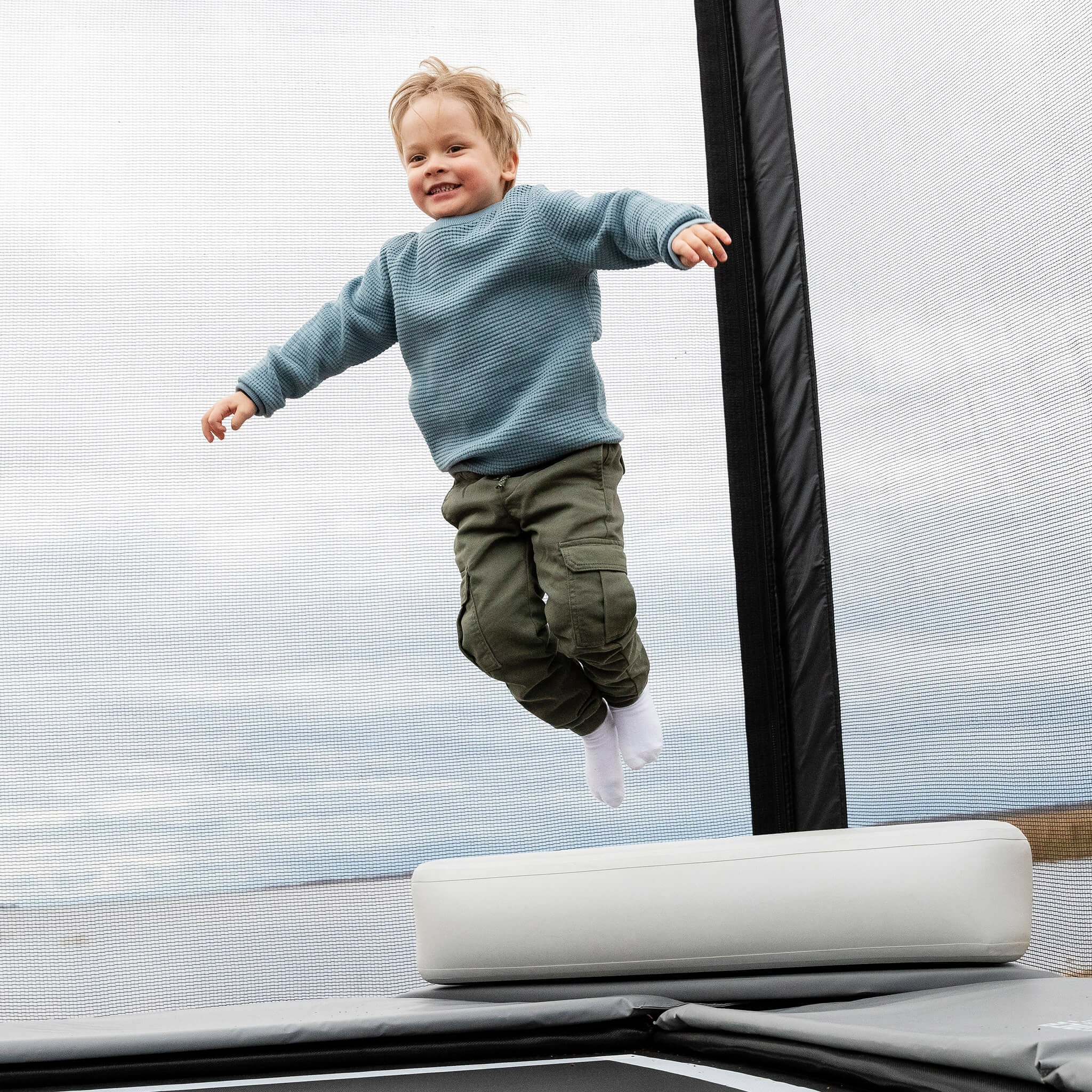 Un petit garçon saute du haut de l'Acon X Triangle Block sur le trampoline.