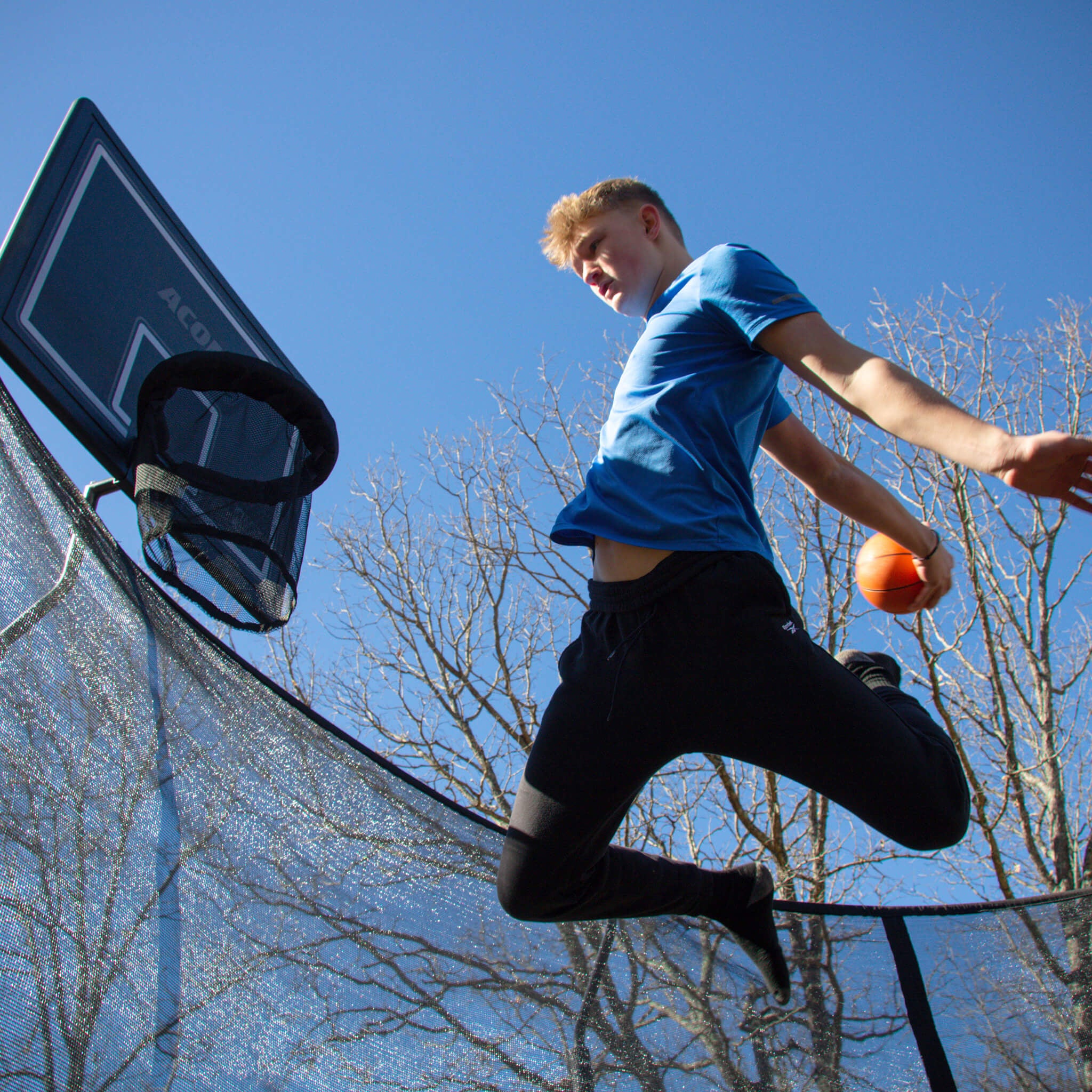 Un garçon joue au basket-ball sur trampoline.